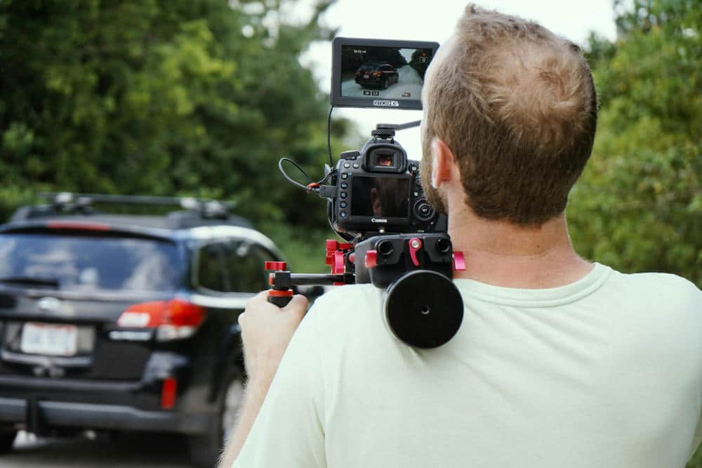 a man films a car with a professional camera