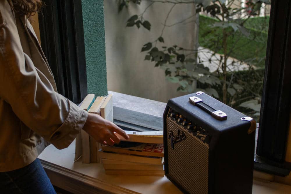 woman standing at the window with books and a guitar amplifier